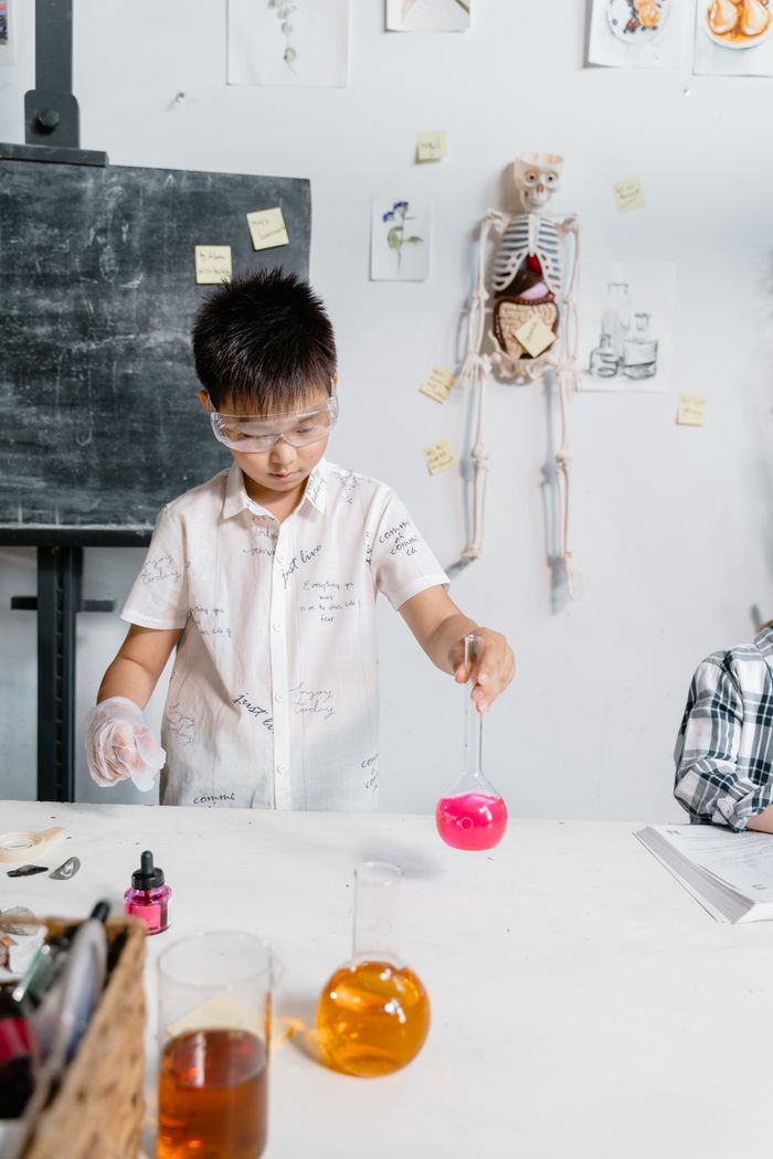 Child engaged in a science experiment with laboratory equipment indoors.